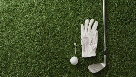 close up of golf club, ball and glove on grass, copy space, slow motion