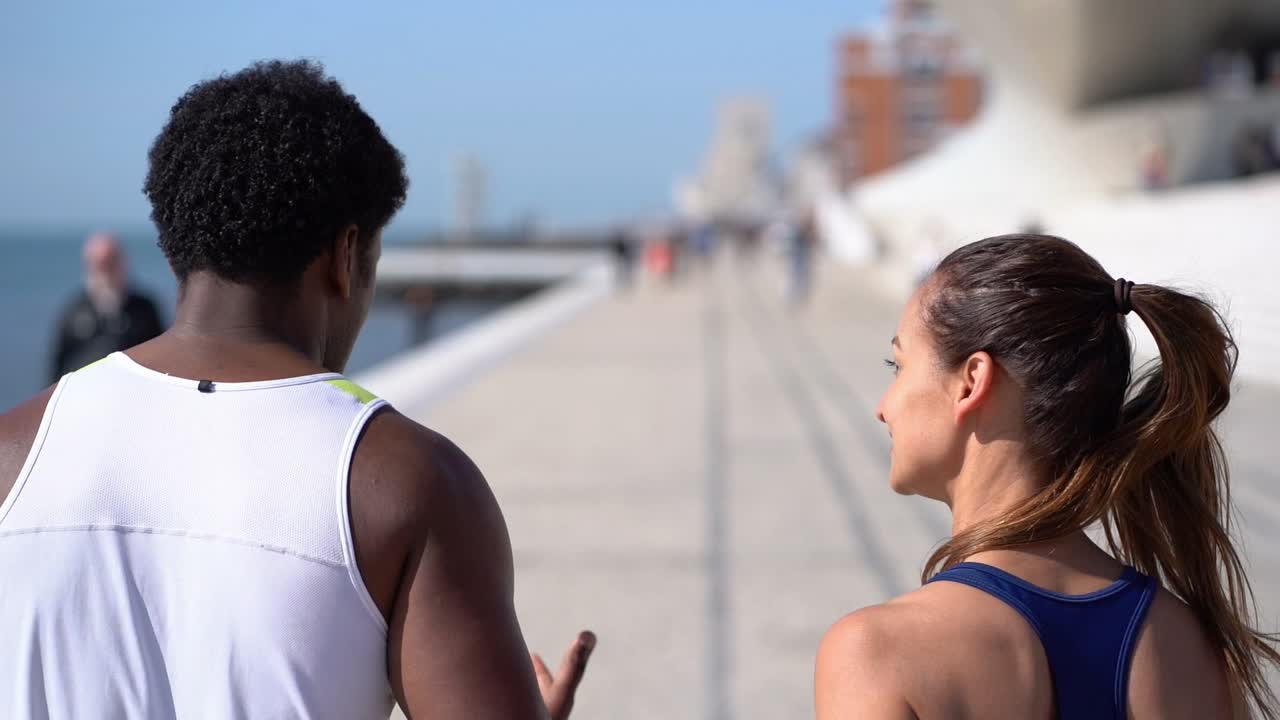 Jovem casal atlético correndo ao longo do aterro.