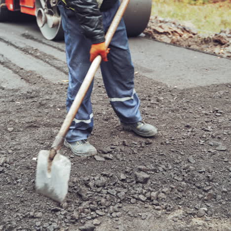 workers in special uniform working with shovels making a new road. compactor machine and workers putting new asphalt. close-up