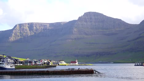 Hvannasund-Kirche-Mit-Rotem-Dach-Am-Vidoy-Fjord-Mit-Malerischer-Berglandschaft-Dahinter,-Färöer-Inseln