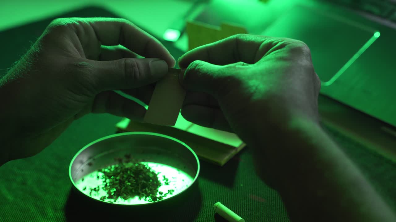 Closeup of joint rolling paper with marijuana hash and tobacco for smoking indoors