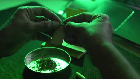 closeup of joint rolling paper with marijuana hash and tobacco for smoking indoors