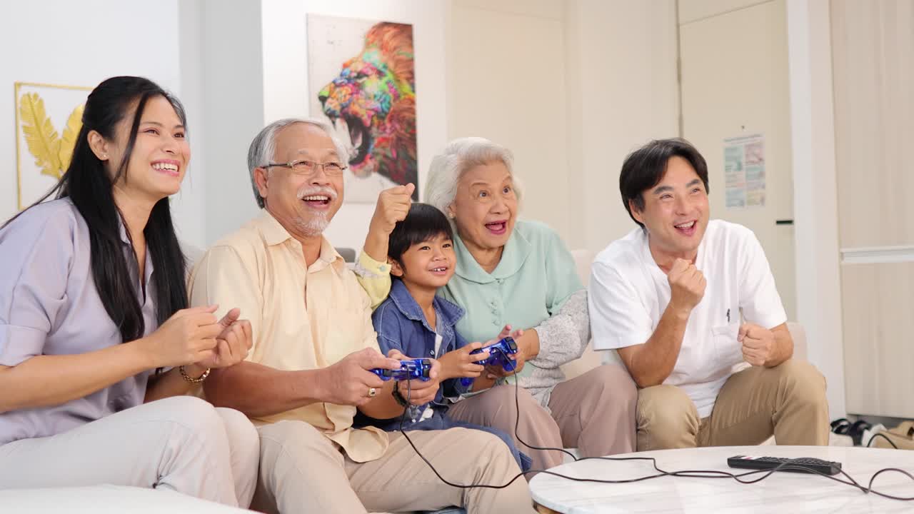 Multigenerational Asian family laughing and playing video games together in a bright, modern living room