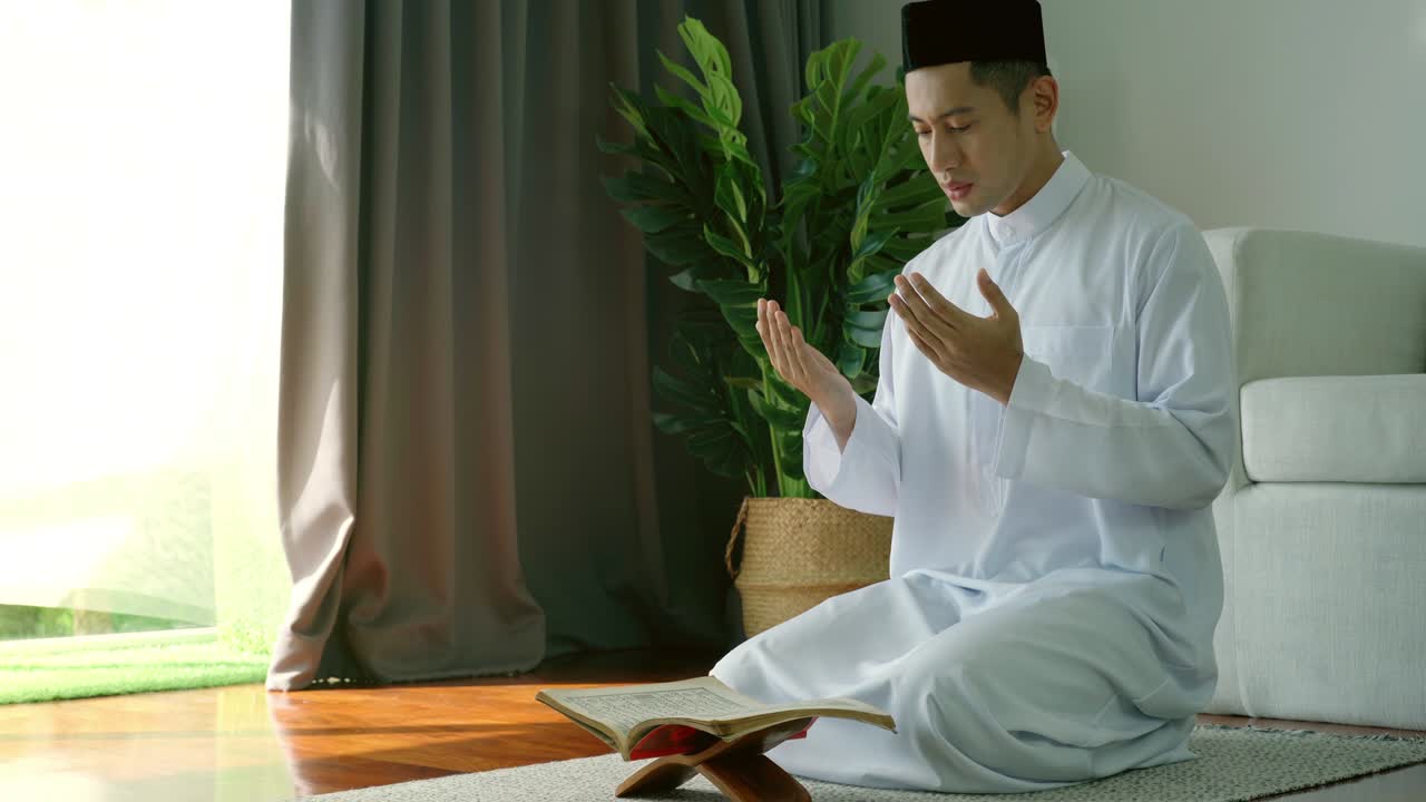 아시아의 무슬림 남자가 집에서 기도하고 드리고 있습니다.