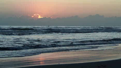 Die-Sonne-Geht-Gerade-über-Den-Wolken-Auf,-Als-Eine-Kleine-Gruppe-Von-Paddelboardern-Und-Surfern-Bei-Sonnenaufgang-An-Der-Beliebten-Burleigh-Gold-Coast-In-Qld,-Australien,-Wellen-In-Einem-Unruhigen-Und-Windigen-Ozean-Fängt