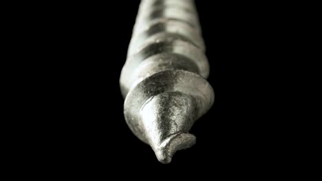 close-up of a metal screw tip against a dark background