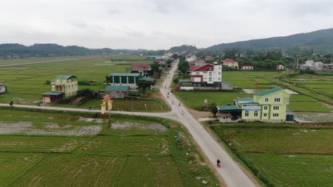 摩托車在鄉村高速公路上行駛的美麗景色,沿著村莊和圍繞著大米田的農場在一個漂亮的平靜的天空