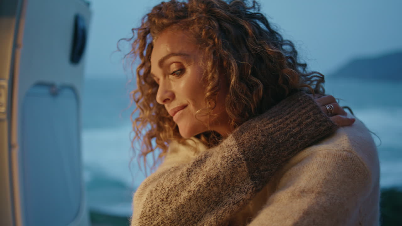 Beautiful tourist resting twilight ocean shore in trailer with open door closeup