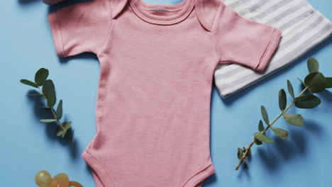 video of pink baby grow, booties and hat with copy space on blue background