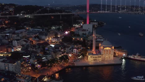 beautiful evening in ortakoy neighbourhood in istanbul at dusk after sunset with mosque by the water, slow aerial forward