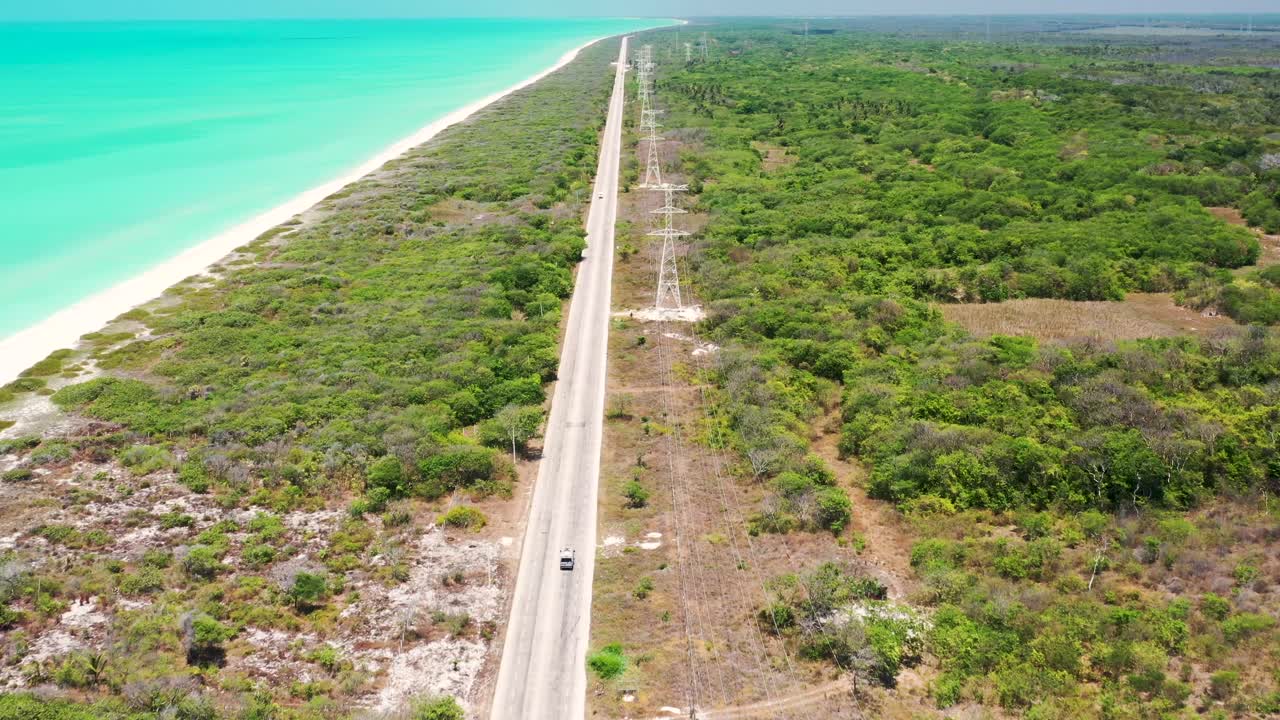toma aérea de drones de un auto conduciendo en una carretera por el golfo de méxico durante el día soleado