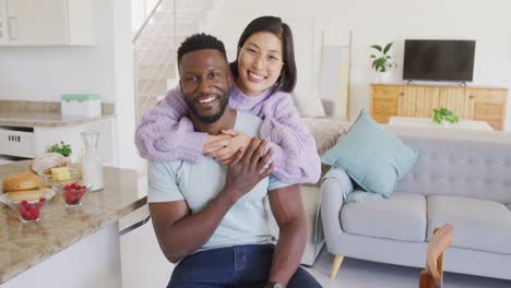 portrait of happy diverse couple embracing in living room