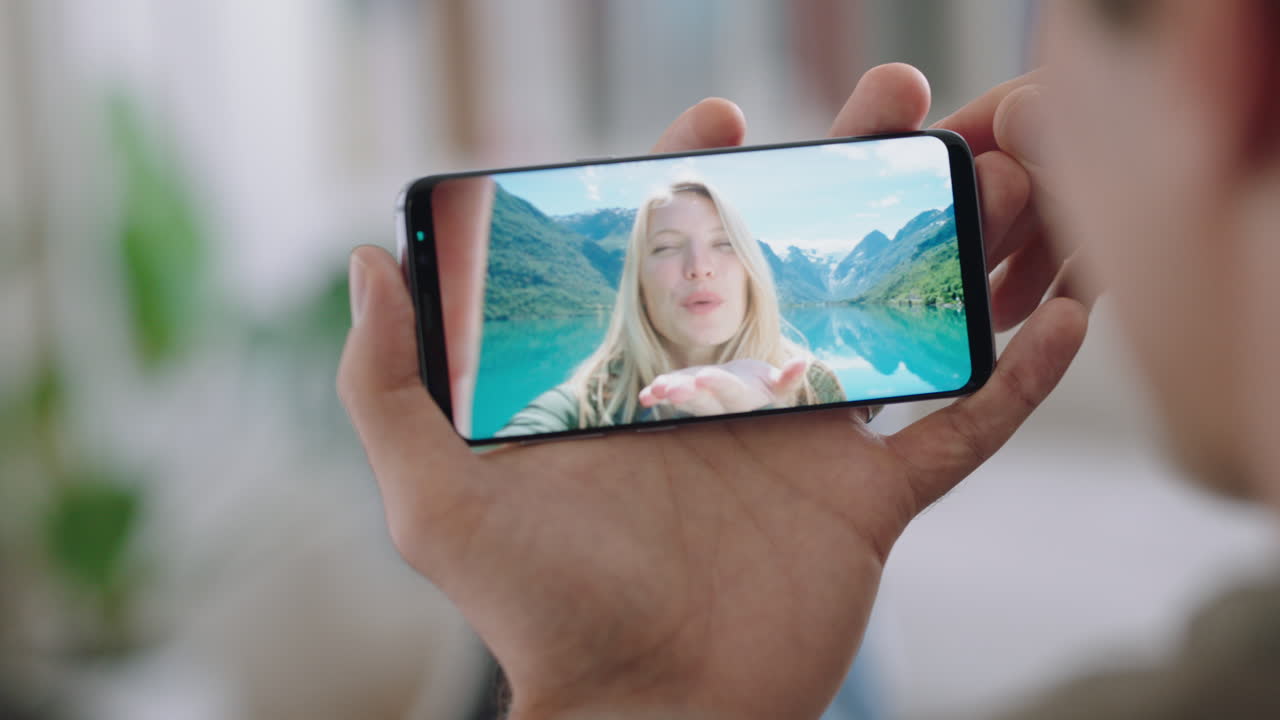 joven chateando en video usando un teléfono inteligente con su novia de vacaciones en noruega compartiendo experiencia de viaje divirtiéndose en la aventura de vacaciones comunicándose en el teléfono móvil imágenes 4k