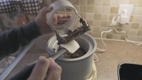 hacer helado de chocolate cremoso en una máquina para hacer helados, de cerca, de mano