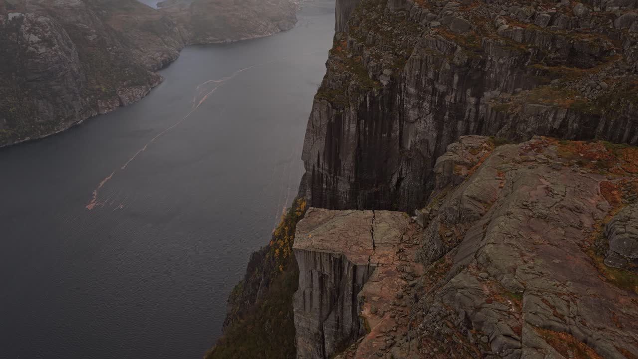 Udsigt fra høj vinkel af ensom vandrer på den dramatiske Preikestolen-klippe ved skumringstid