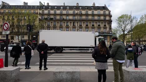 people waiting as a truck passes by