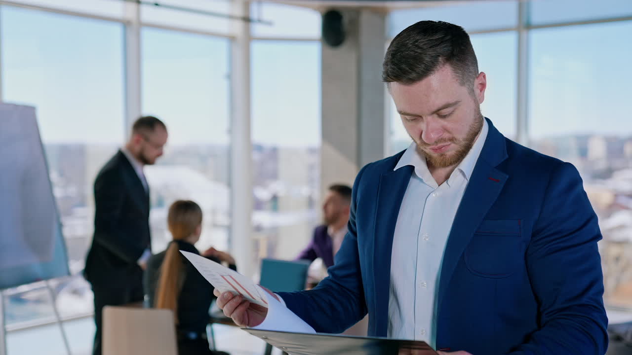 Businessmen working in office. Portrait of a handsome young entrepreneur thinking of new project in the modern business center on his colleagues background.