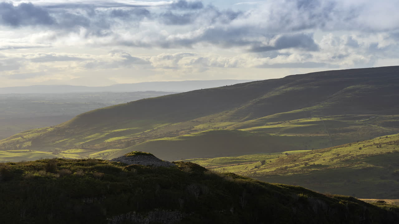 아일랜드 카운티 슬라이고에 있는 캐로킬에서 바라본 화창한 날 동안 먼 거리에 무덤을 만든 선사시대 사람과 시골 자연 언덕 쪽 풍경의 시간 경과