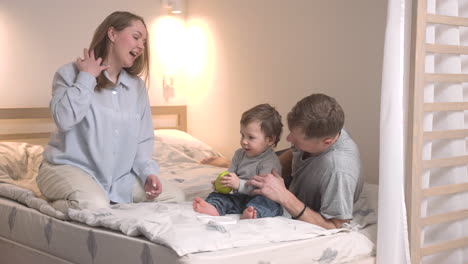 Baby-Und-Seine-Eltern-Sitzen-Auf-Dem-Bett