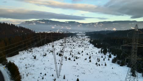 close drone shot of powerlines running through snowy winter landscape