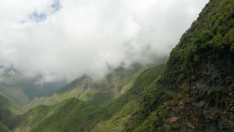 Majestic-green-mountains-with-low-clouds-covering-peaks,-aerial