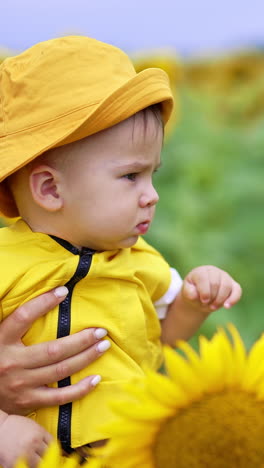 baby in a yellow hat and clothes in a sunflower field