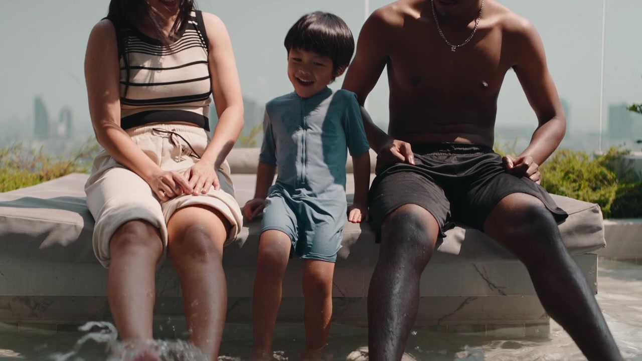 Famiglia seduta a bordo piscina panoramica e schizzi d'acqua