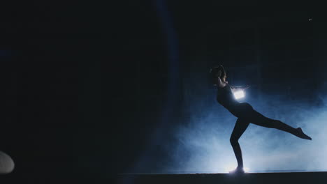 Women's-Artistic-Gymnastics.-In-slow-motion-in-the-smoke,-the-girl-performs-complex-elements-of-the-Olympic-program-on-a-balance-beam.