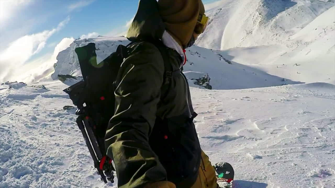 카메라를 향해 손을 흔들며 스노보드를 타고 내려가는 남성