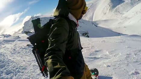 male waving to the camera and goging down on his snowboard