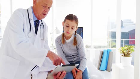un médico discutiendo con una chica sobre una tableta digital
