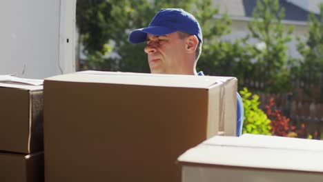 male postal service courier checking packages in mail truck