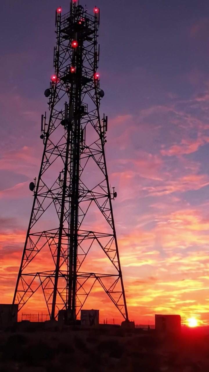 Una impactante escena de atardecer con una torre contra un cielo vibrante, destacando la interacción entre la tecnología y la belleza de la naturaleza en siluetas únicas