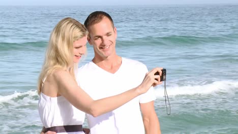 panorama of couple on the beach taking photos of themselves