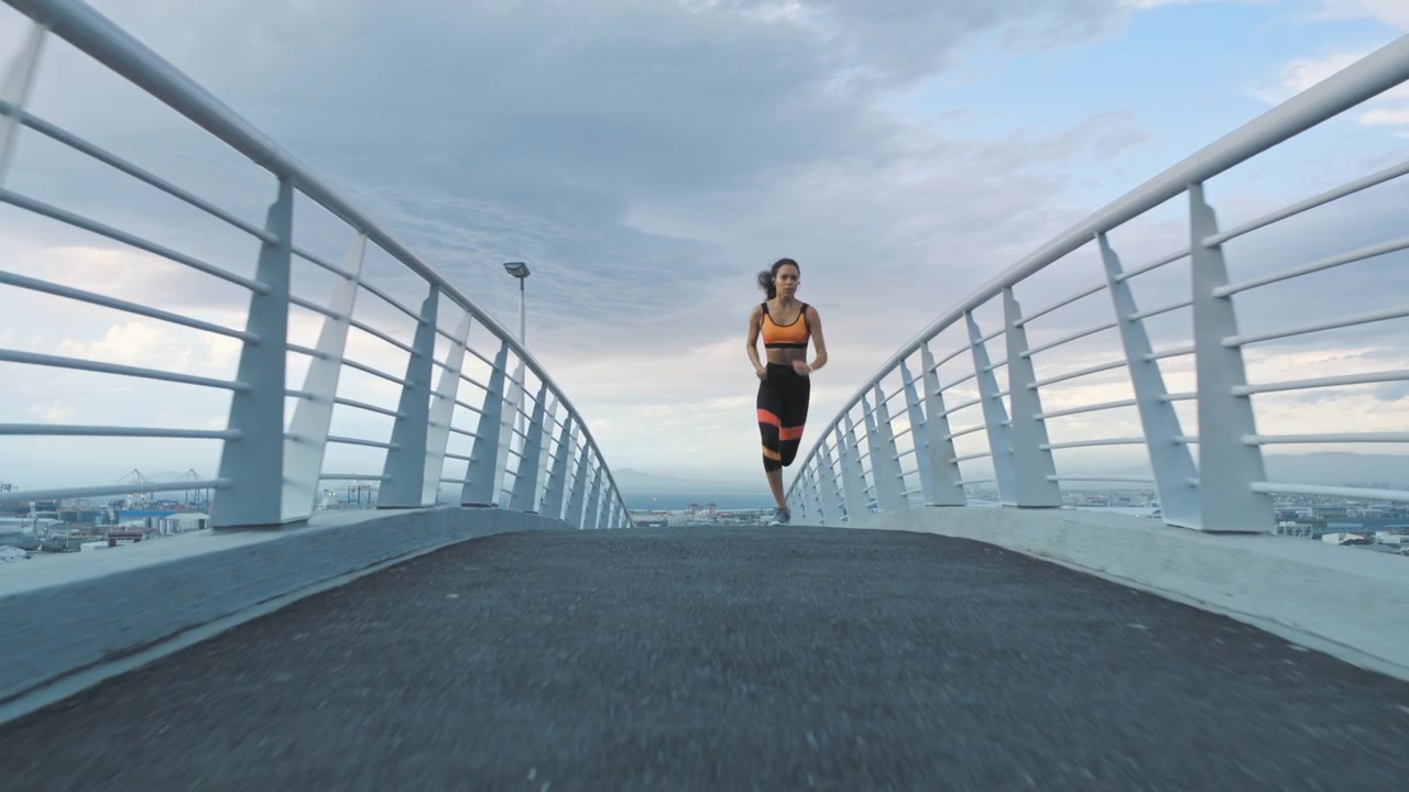 Young Woman Running Across Modern Pedestrian Bridge
