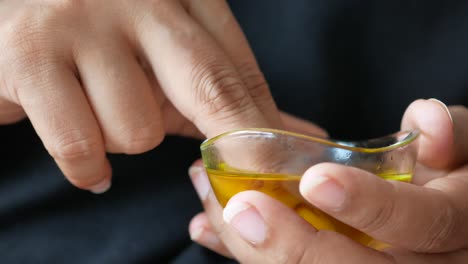 persona que sostiene un cuenco de vidrio de aceite de oliva