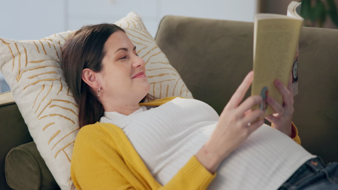 Pregnant woman reading a book on the couch