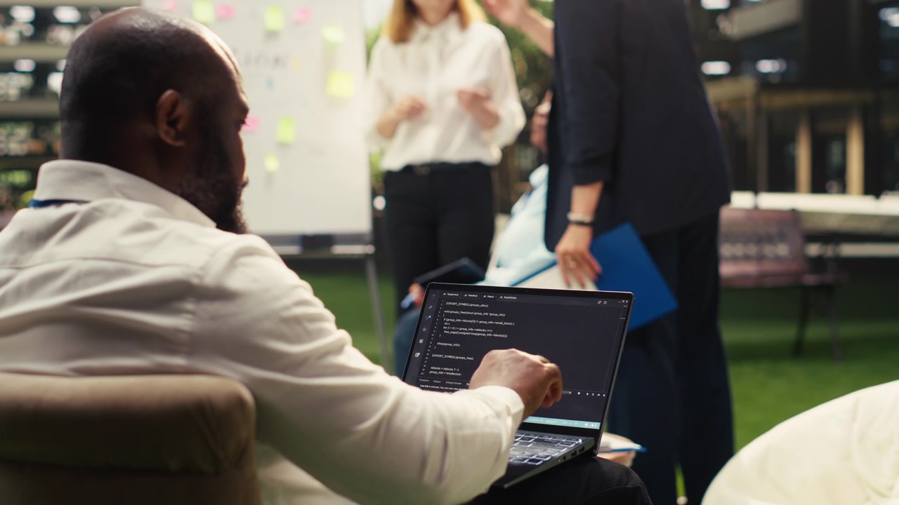 Software Developer Coding on Laptop During Office Team Meeting