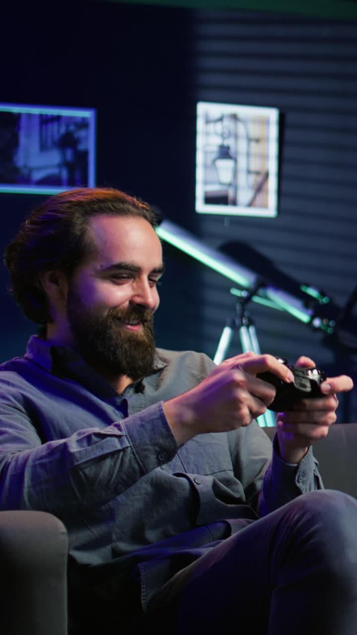 Vertical video Man enjoying playing videogame in neon lit room, holding controller