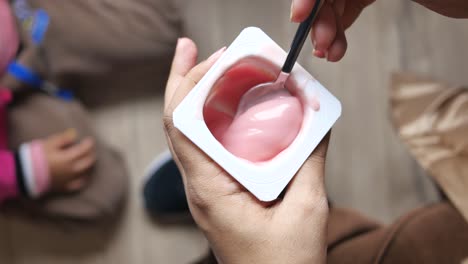 woman eating pink yogurt with a spoon