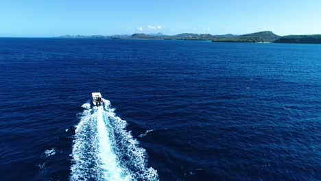 Drone-rises-above-dive-tour-boat-cruising-in-caribbean-deep-blue-ocean-water