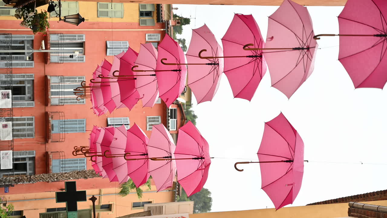 Street scape of Grasse, France. Narrow street with rows of pink umbrellas