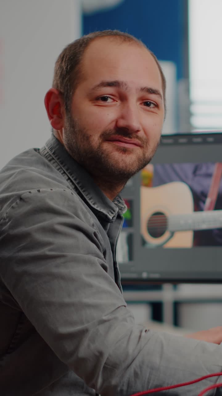 Vertical video Videographer smiling at camera working on computer