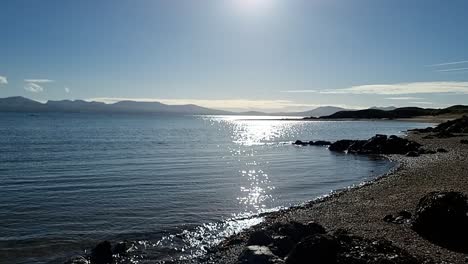 Slow-motion-tide-waves-splashing-under-heavenly-hazy-sunrise-Snowdonia-mountain-range-skyline