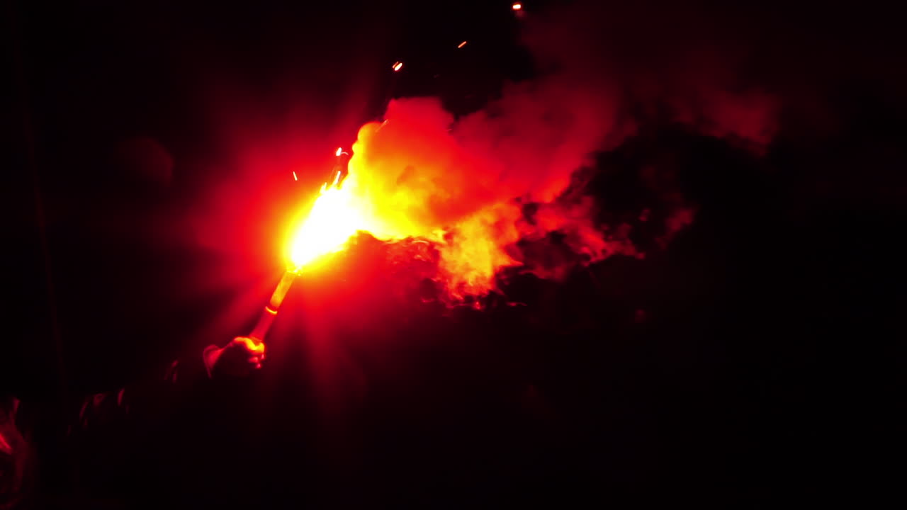 humo blanco ondulante y una llama roja intensa de una bengala de mano de emergencia