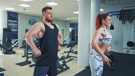 man and woman posing with their athletic body in fitness center. attractive couple with muscular bodies doing exercises in the gym.