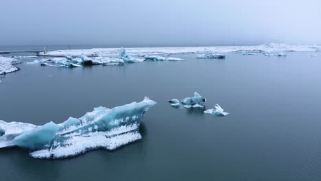 aerial panning shot of glacial lake jo kulsa rlo n with icebergs during cloudy day in iceland