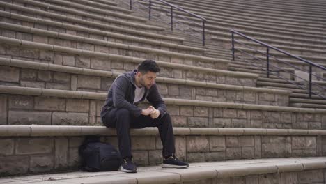 hombre triste y solitario sentado en el suelo al aire libre en la ciudad estresado y cansado.