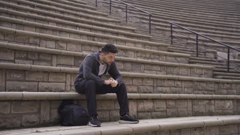 sad lonely man sitting on the ground outdoors in the city stressed and tired.