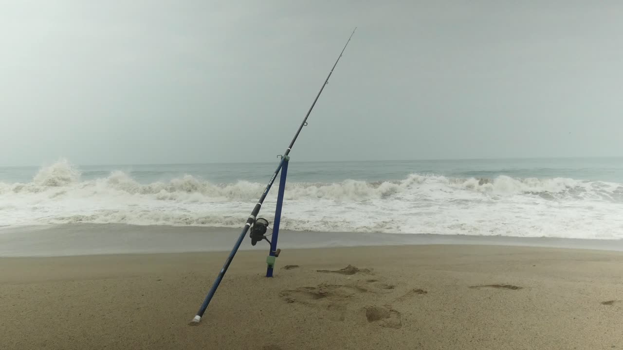 una caña de pescar de pie en un pico de arena utilizado para surfear la pesca